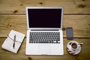 Picture of Laptop, notebook and coffee tp symbolise copywriter at work